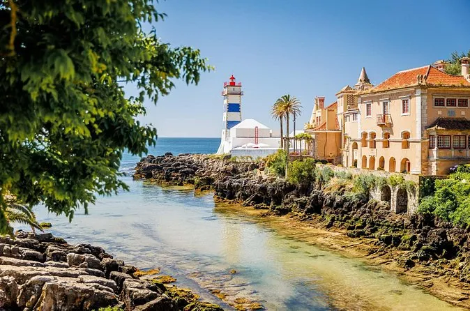 The small Santa Marta lighthouse in Cascais beside a rocky cove and a yellow house