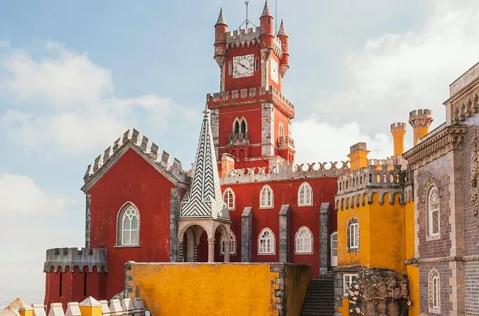 The red clock tower of Pena Palace with yellow walls and a blue sky