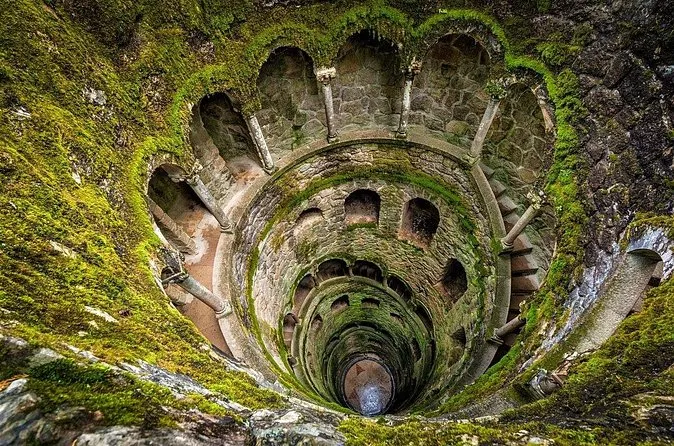 The mossy spiral galleries of the Initiation Well with a small opening of light at the bottom